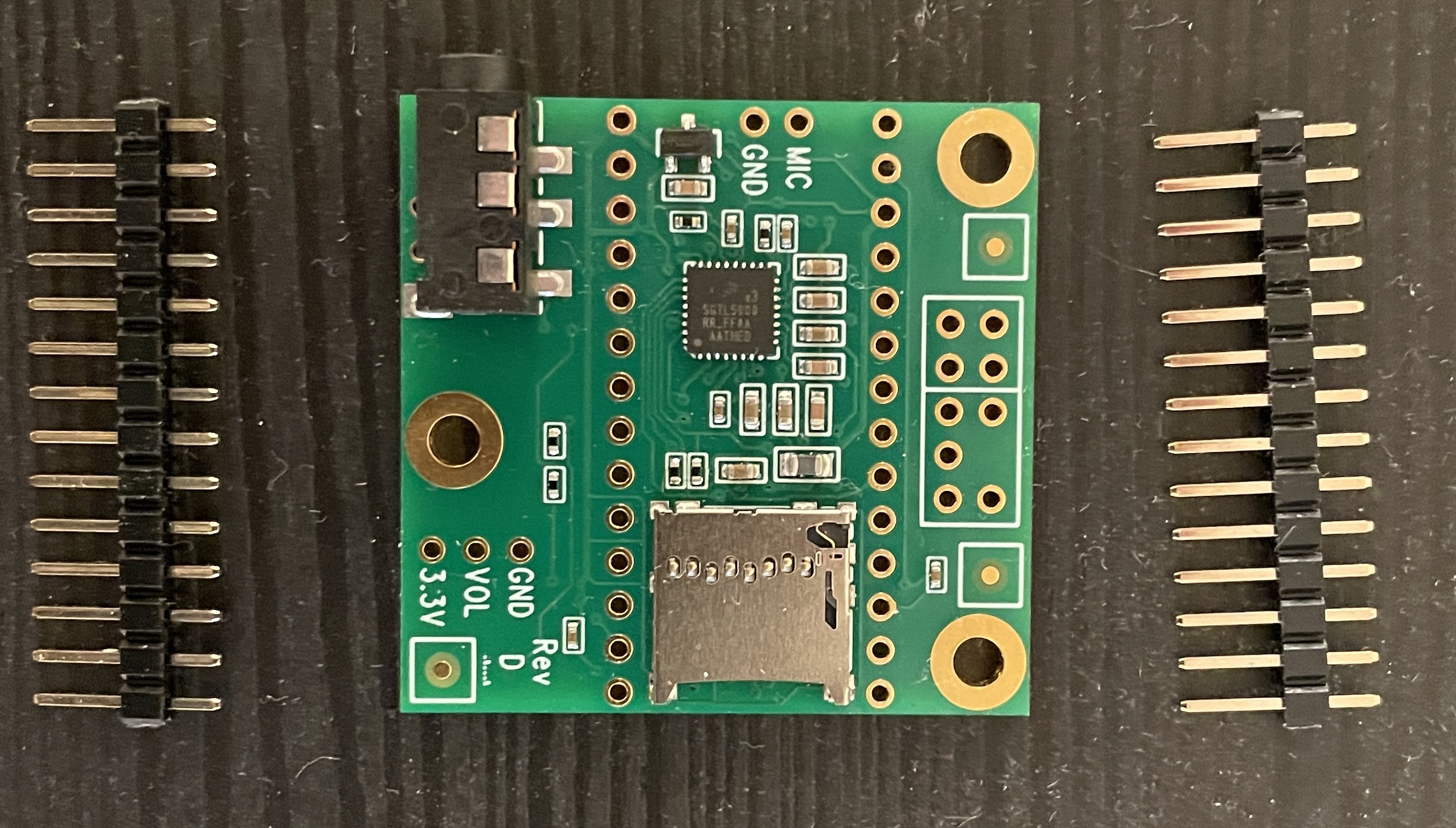 The Teensy 4.x audio shield with unsoldered header pins lying next to it on a table showing that the pins are longer than standard headers